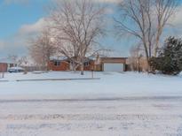 Brick ranch house with attached garage, nestled on a snow-covered lot at 1466 Elmwood Ln, Denver, CO 80221