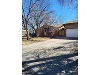 Charming single-story brick home with a driveway and a well-maintained front yard on a sunny day at 1466 Elmwood Ln, Denver, CO 80221