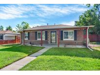 Charming brick home featuring a well-manicured lawn and inviting curb appeal at 2810 Oneida St, Denver, CO 80207
