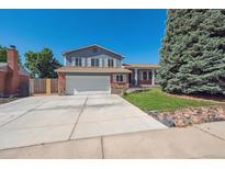 Two-story home with blue siding, brick accents, a two-car garage, and mature landscaping at 9442 W Walden Ave, Littleton, CO 80128