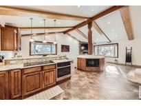 Spacious kitchen with wooden beams, granite counters, stainless appliances, and lots of sunlight at 7552 Miller Ct, Arvada, CO 80005