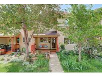 Charming home exterior with a welcoming porch swing, red wood trim, lush garden, and mature trees enhancing curb appeal at 1460 Quince Ave # 102, Boulder, CO 80304