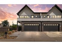 Modern townhome showcasing brick accents, sleek black garage doors, and a neutral color palette against a vibrant sunset sky at 5240 N Raleigh St, Denver, CO 80212