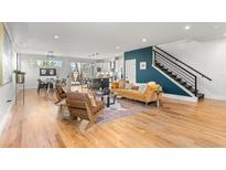 Open-concept living room with modern furnishings, hardwood floors, and a staircase in a bright and airy space at 5240 N Raleigh St, Denver, CO 80212