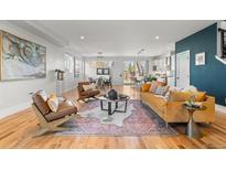 Open-concept living room featuring hardwood floors, designer furnishings, and abundant natural light at 5240 N Raleigh St, Denver, CO 80212