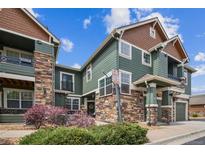 Beautiful townhome with green siding, stone accents, and well-maintained landscaping, creating inviting curb appeal at 7080 Simms St # 105, Arvada, CO 80004