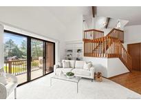 Bright living room boasts a vaulted ceiling, sliding glass doors to deck, and elegant staircase at 501 Manhattan Dr # 202, Boulder, CO 80303