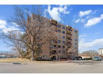 Multi-story brick condo building with balconies, trees, and a partly cloudy sky at 3675 S Cherokee St # 208, Englewood, CO 80110