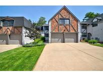 Charming Tudor-style townhome with a brick and white exterior, two-car garage, and well-manicured lawn at 5821 E Ithaca Pl, Denver, CO 80237