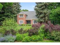 Charming brick home featuring lush landscaping with trees, bushes, and grass lawn at 7 Cherry Hills Farm Dr, Cherry Hills Village, CO 80113