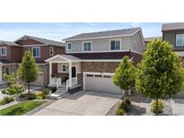 Charming two-story home with brick accents, a well-manicured lawn, and an attached two-car garage at 5297 Blue Lunar Ln, Castle Rock, CO 80104