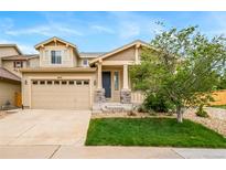 Tan two-story home features a two-car garage, covered porch, and well-maintained lawn at 4850 Bluegate Ln, Highlands Ranch, CO 80130