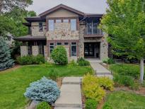 Charming two-story stone home featuring a lush front yard and a welcoming entrance at 230 Hudson St, Denver, CO 80220