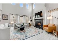 Bright living room with fireplace, high ceilings, large windows, neutral tones, and comfortable seating area at 9375 Joyce Way, Arvada, CO 80007
