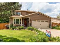 Charming two-story home with a well-maintained lawn and colorful landscaping, a two car garage, and stone accents at 6687 Devinney Ct, Arvada, CO 80004