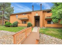 Charming condo exterior featuring a well-maintained lawn and wooden bridge entrance at 3335 S Ammons St # 6-105, Lakewood, CO 80227
