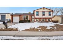Brick ranch home with attached garage and snowy front yard at 1663 S Yampa Way, Aurora, CO 80017