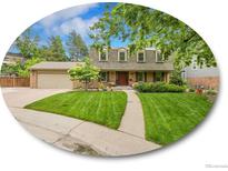 Charming home featuring a lush lawn, mature trees, and a welcoming front porch at 7030 S Fillmore Ct, Centennial, CO 80122