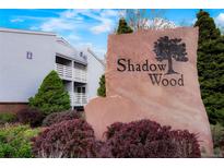 Stone community sign for Shadow Wood surrounded by colorful bushes and a view of the apartments at 7665 E Eastman Ave # 302B, Denver, CO 80231