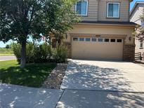 Tan two-story house with a two-car garage and landscaped front yard at 21829 E Layton Dr, Aurora, CO 80015