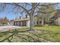 Residential garages attached to tan brick condominium with manicured green grass lawn at 4250 S Olive St # 102, Denver, CO 80237