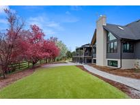 Landscaped backyard with vibrant trees, a spacious lawn, and modern home exterior at 5859 E Ida Pl, Greenwood Village, CO 80111