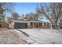 Ranch-style home with large garage and snow-covered front yard at 4712 S Wabash St, Denver, CO 80237