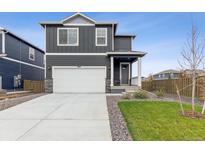 Two-story home with gray siding, white garage door, and landscaped lawn at 847 Ledge St, Lochbuie, CO 80603