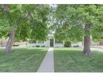 Charming home with mature trees, green lawn, and a concrete walkway leading to the front door at 2812 Krameria St, Denver, CO 80207