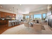 Open-concept living room boasts a breakfast bar, fireplace, and large windows with picturesque neighborhood views at 17097 W 87Th Ave, Arvada, CO 80007