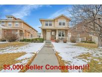 Inviting two-story home with a stone facade, front porch and wintry lawn at 23601 E Mississippi Cir, Aurora, CO 80018