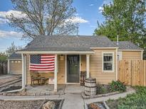 Charming home featuring an inviting front porch decorated with an American flag and rustic barrel planters at 530 S Ames St, Lakewood, CO 80226