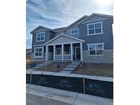 New two story home showing a gray exterior, stone accents, covered porch, and a concrete walkway at 15267 Fillmore St, Thornton, CO 80602