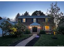 Charming brick home featuring a walkway to the front door, set amongst a well-manicured lawn at 6953 S Prescott St, Littleton, CO 80120