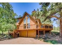 Two-story home with wood siding, a large deck, and a two-car garage, surrounded by mature trees at 643 Aspen Rd, Golden, CO 80401