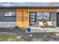 Inviting front entrance with modern wood accents, black framed windows, and cozy outdoor seating at 9309 Highland Pl, Arvada, CO 80002