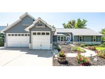 Charming gray house boasts an attached 2-car garage and a walkway with flowers in the front yard at 995 Chase St, Lakewood, CO 80214