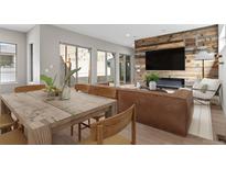 Bright open-concept living room features hardwood floors, modern furnishings, and a rustic wood accent wall with a fireplace at 15525 W La Salle Ave, Lakewood, CO 80228