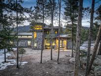 Stunning modern home showcasing unique architectural details and natural stone accents nestled among towering trees at 11505 Conifer Ridge Dr, Conifer, CO 80433
