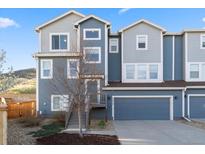 Charming townhome with modern blue siding, a well-maintained yard, and an attached garage at 1828 Blue Oak Ct, Castle Rock, CO 80104