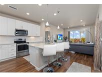 Bright eat-in kitchen featuring white cabinets, stainless steel appliances, and breakfast bar seating that overlooks the living area at 420 E Fremont Pl # 309, Centennial, CO 80122