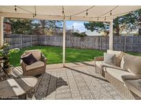Relaxing back patio with wicker furniture and a well-manicured backyard, perfect for outdoor entertaining at 4762 S Clay Ct, Englewood, CO 80110