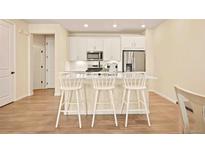Modern kitchen with white cabinetry, stainless steel appliances, and breakfast bar with seating at 8055 Navajo River Loop # B, Littleton, CO 80125