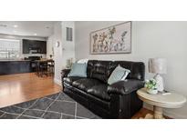 Living room features a dark leather sofa, hardwood floors and modern decor at 8187 Martin Luther King Blvd, Denver, CO 80238