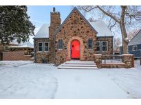 Charming brick home with a red door and snowy front yard at 150 Harrison St, Denver, CO 80206