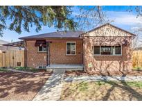 Charming brick home featuring a well-manicured lawn and cozy, covered front porch at 5611 E 13Th Ave, Denver, CO 80220