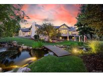 Beautiful home exterior featuring a bridge over a pond and lush landscaping at sunset at 10145 Meadow Run, Parker, CO 80134