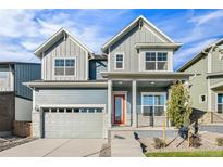 Charming two-story home featuring a two-car garage and a welcoming porch with a vibrant orange door at 21097 E 62Nd Dr, Aurora, CO 80019