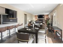 Inviting dining room with seating for six, flowing into a living room with a stone fireplace feature at 7669 Pecos St, Denver, CO 80221