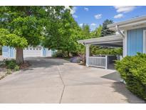 Light blue house featuring a covered patio, spa, garage and mature landscaping at 2225 Linda Vista Dr, Lakewood, CO 80215